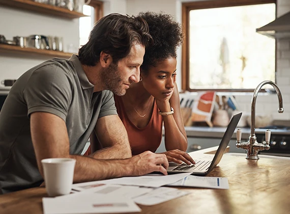 a couple looks at a laptop in the kitchen