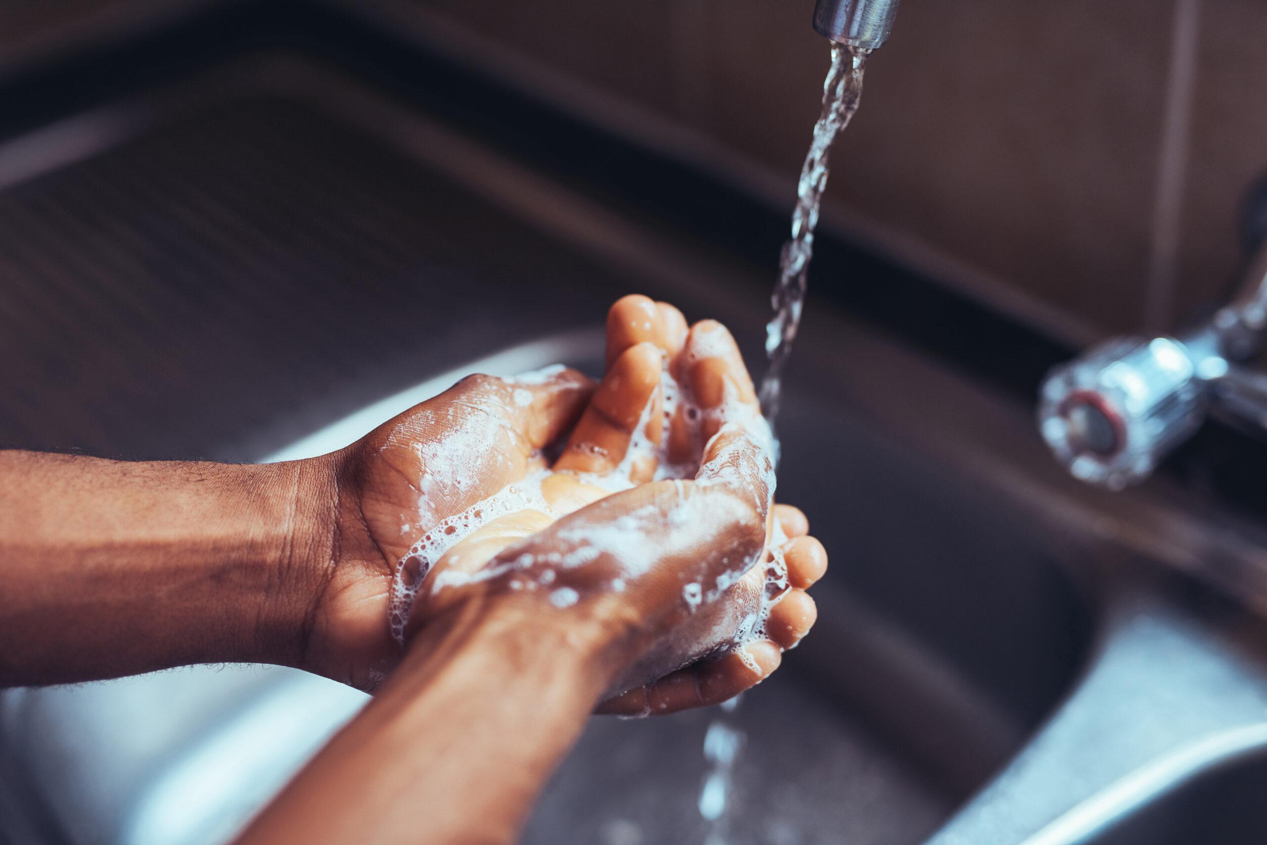 Person washing hands in a kitchen sink 