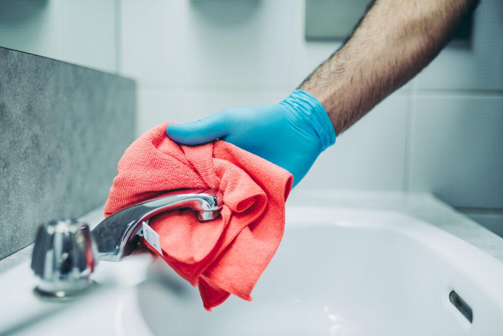 A man wipes a faucet with a red cloth