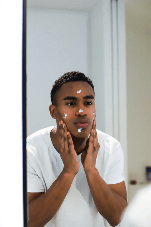 A man applying moisturiser in the mirror