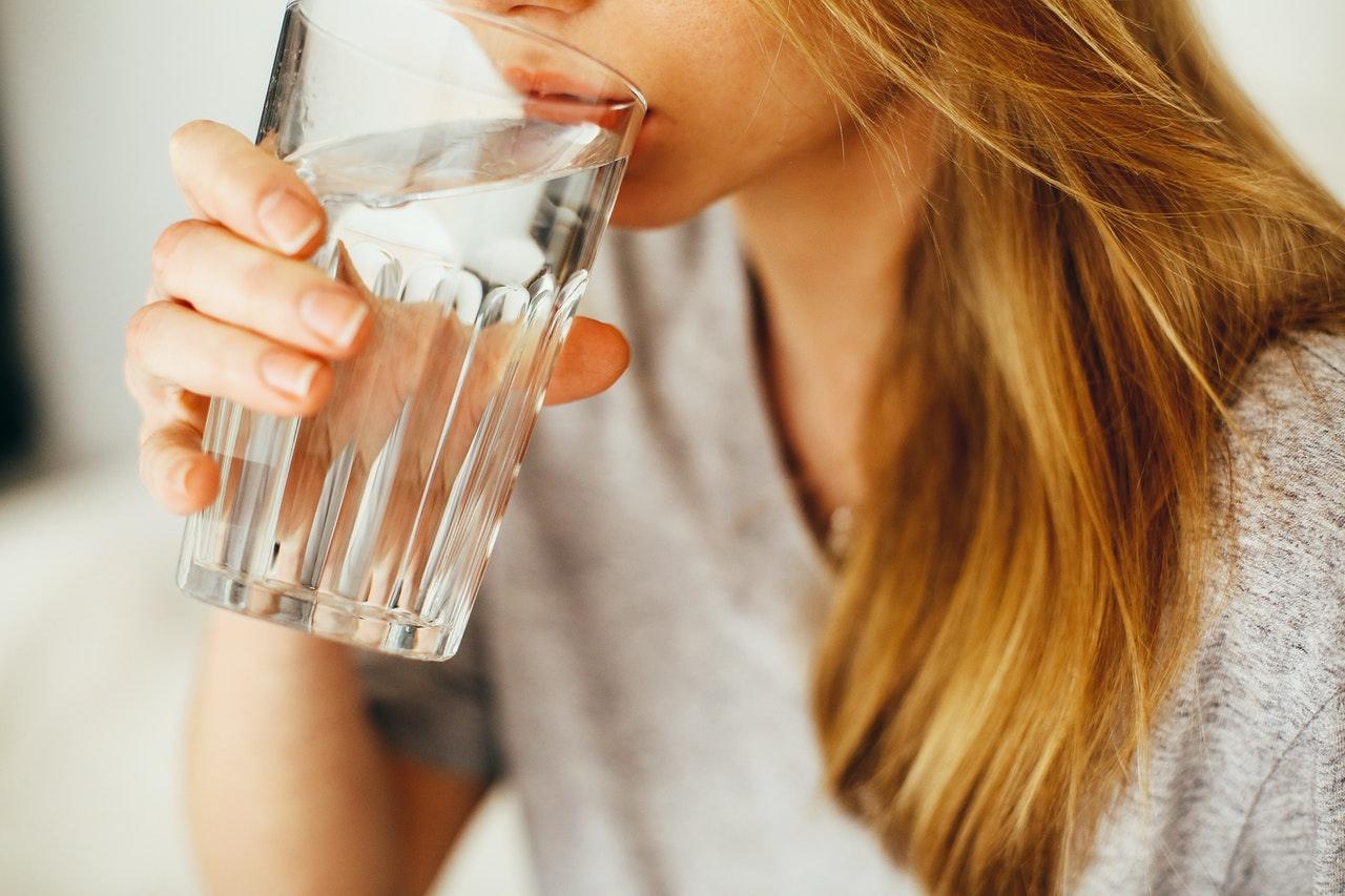 A woman drinks purified water from a large glass